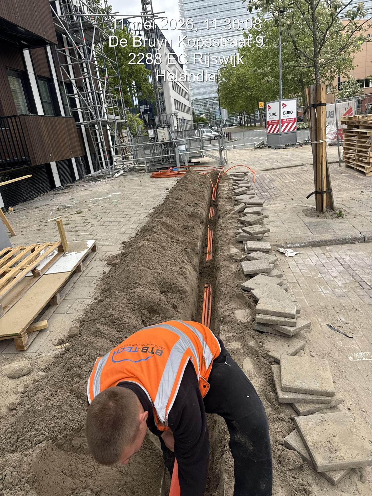 Monteur legt glasvezelbuizen in een sleuf bij nieuwbouwproject Novum in Rijswijk