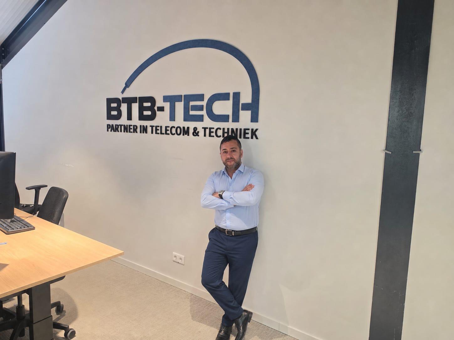 Saleh Karbalai, supply chain manager bij BTB-Tech, voor de logowand op het hoofdkantoor