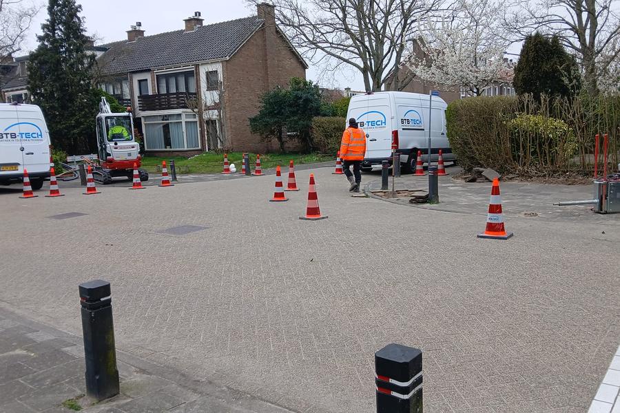 Twee servicebussen en een minigraver bij graafwerk aan een kabeltracé